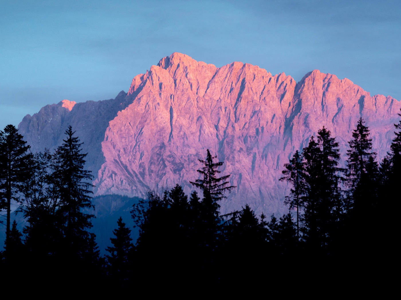 Высокие горы в лучах солнца у хвойного леса 