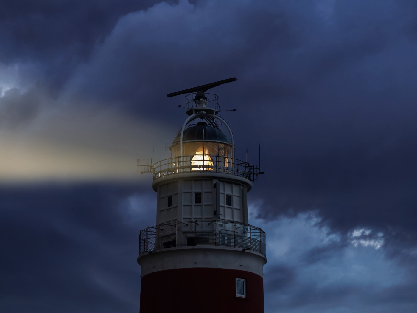 Грозовое небо над включенным маяком ночью