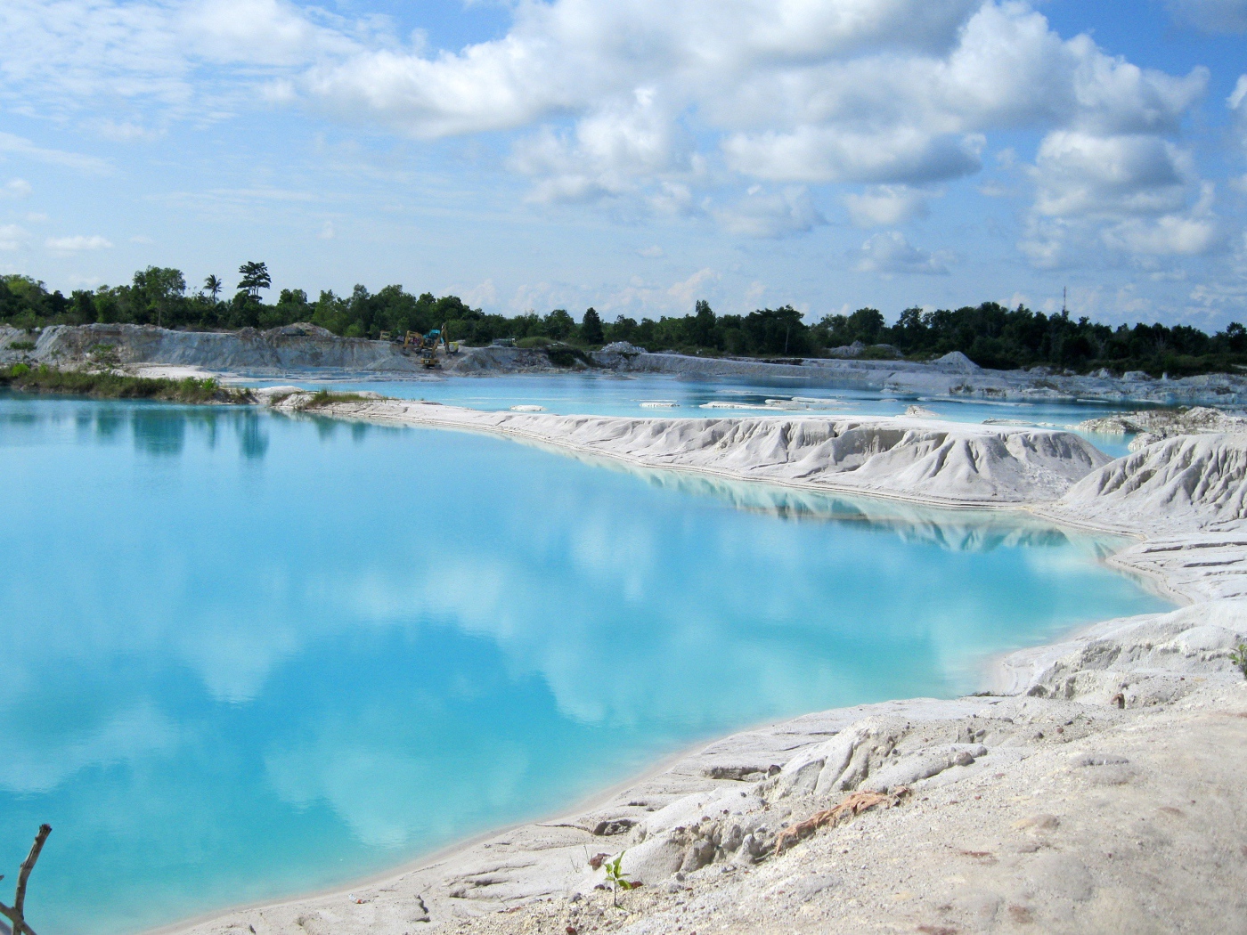 Белый песок на берегу водоема с голубой водой 