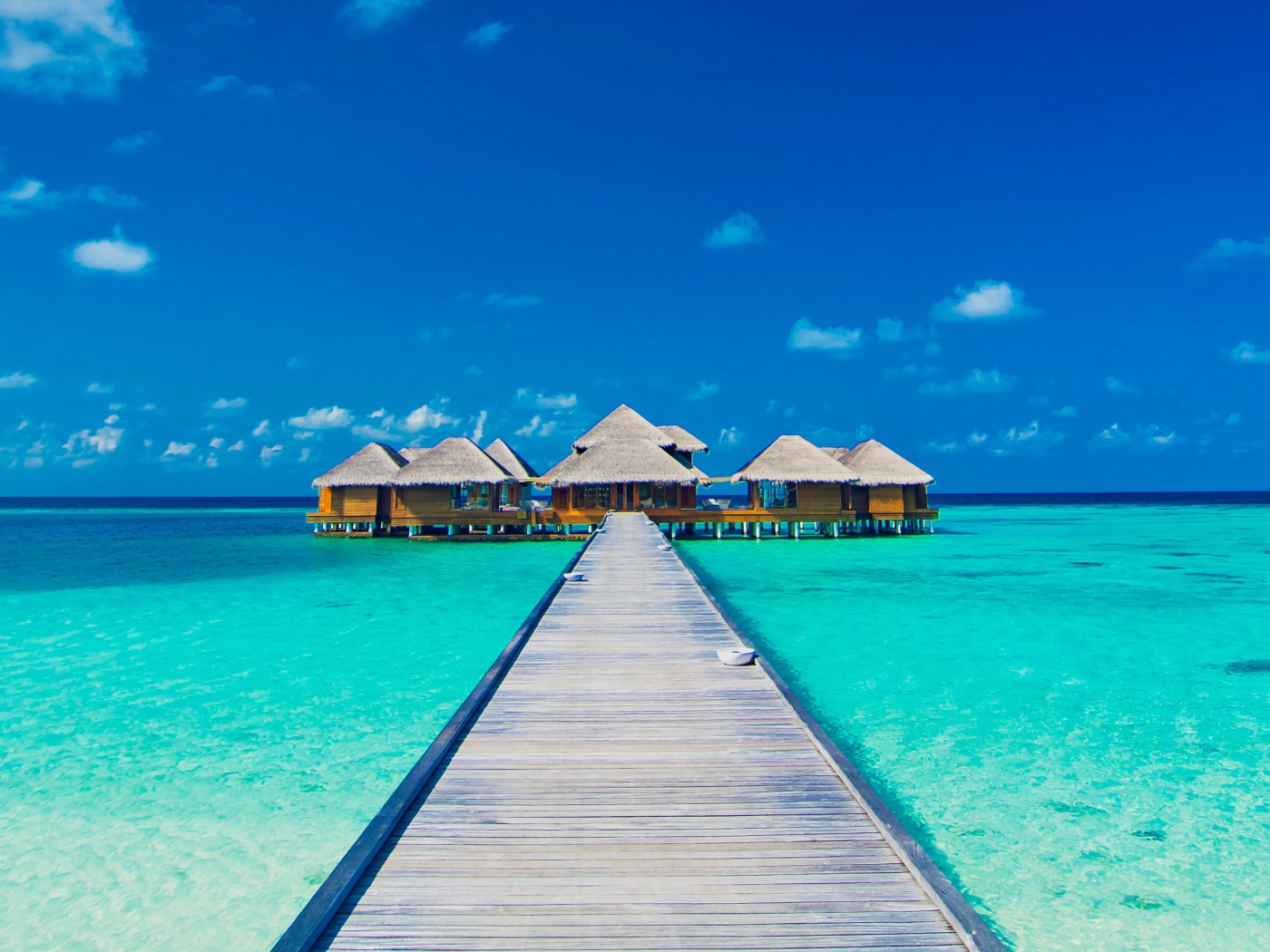 Деревянный мост к домам на сваях в голубом океане 