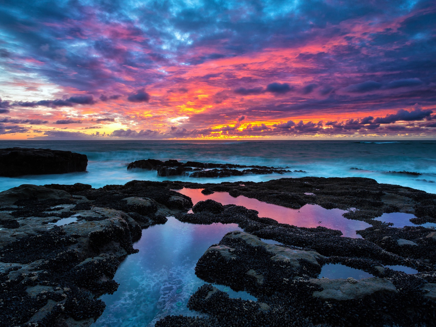 Восход яркого солнца над камнями в море