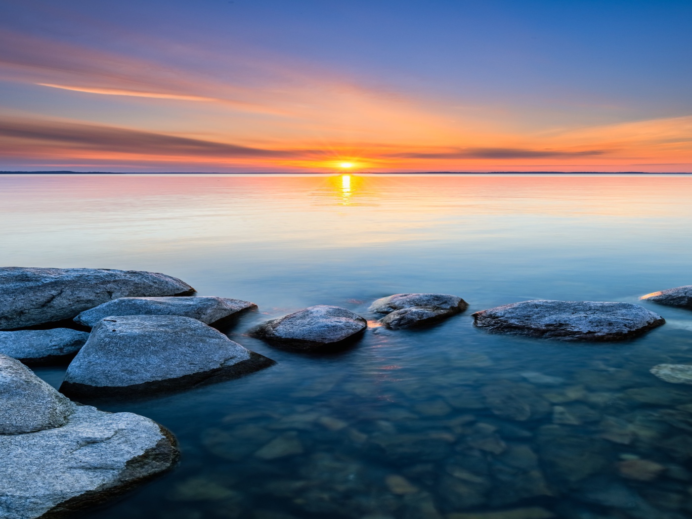 Большие камни в воде на закате яркого летнего солнца 