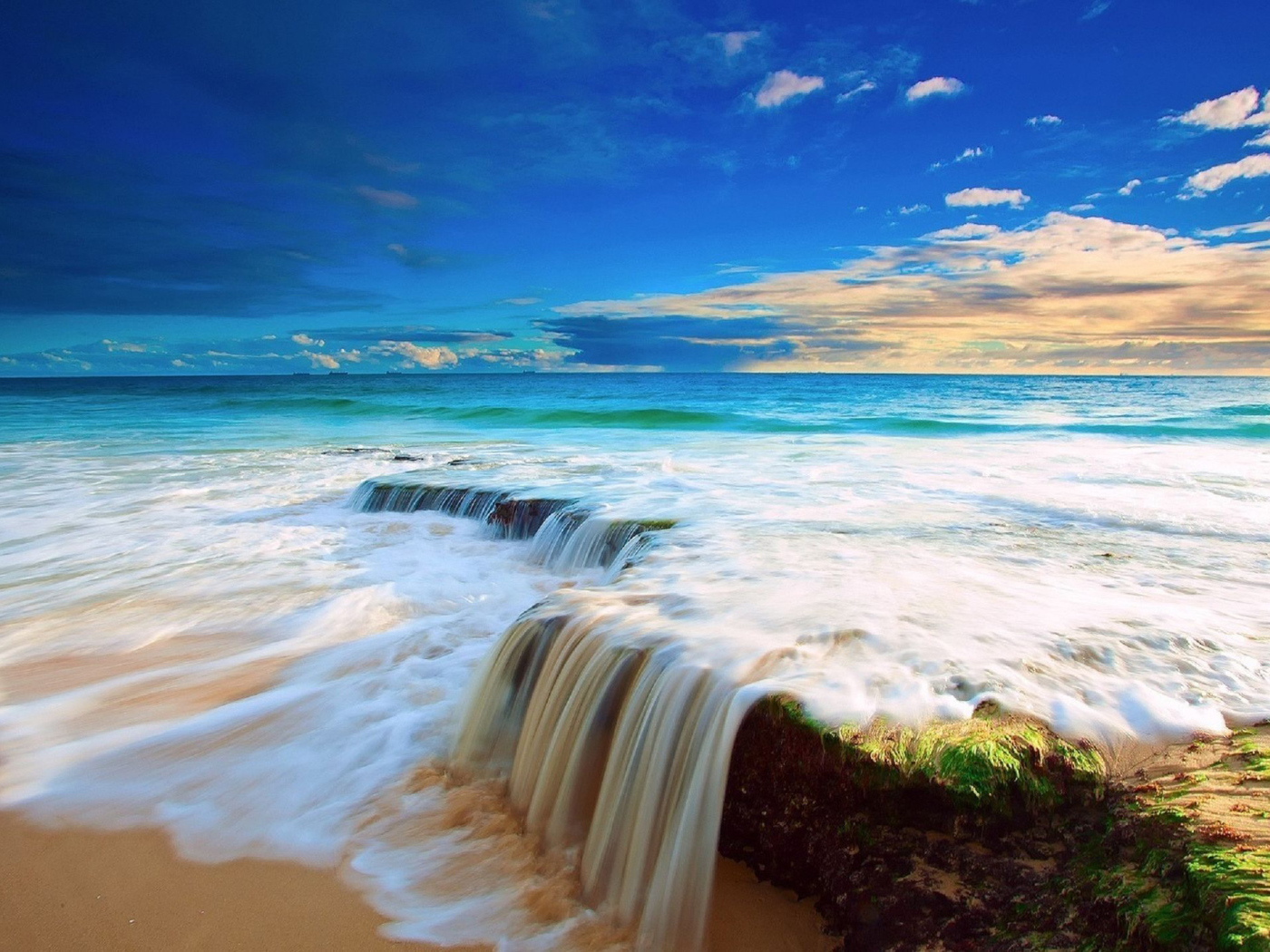 Белые волны бушующего океана на песке под голубым небом
