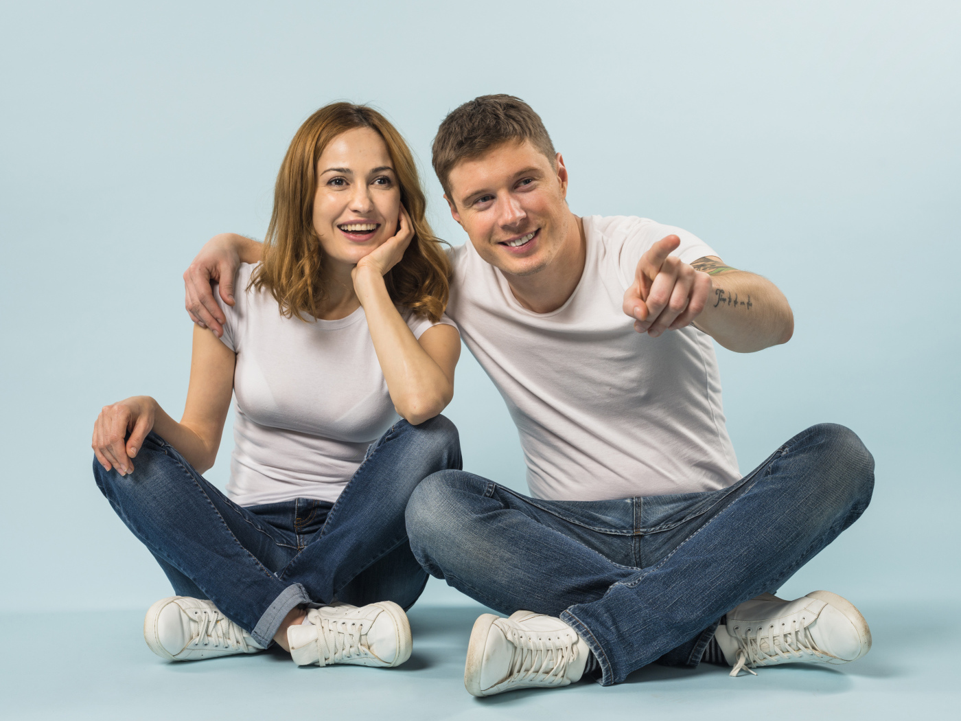 Мужчина и девушка сидят на полу на голубом фоне
