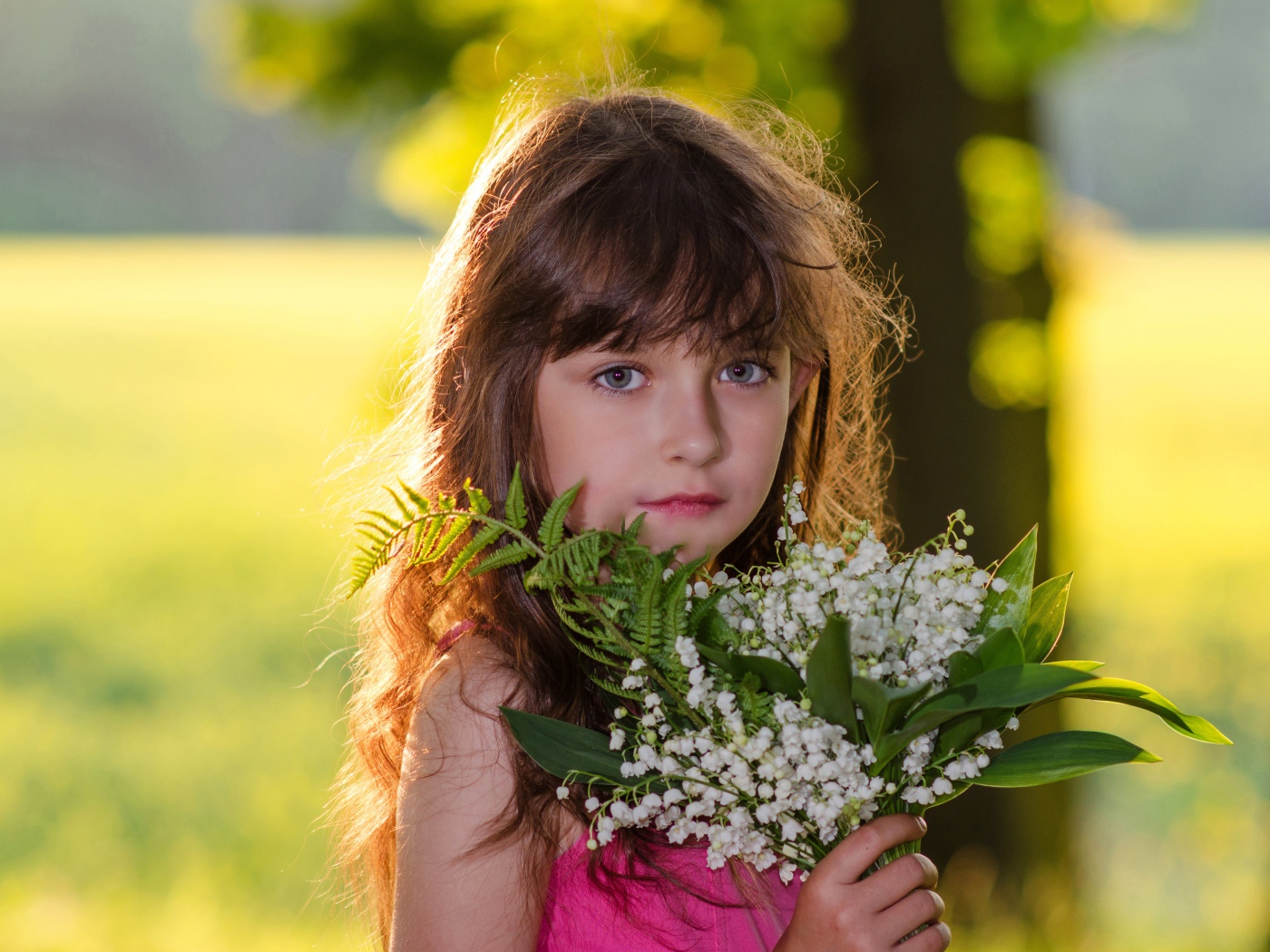 Красивая маленькая девочка с букетом ландышей в руке