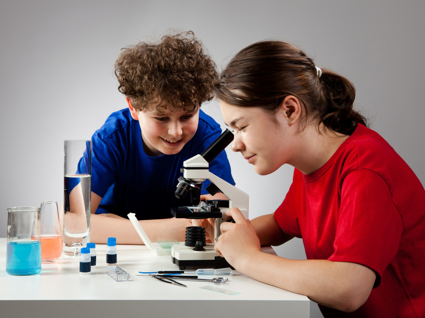 Мальчик и девочка смотрят в микроскоп 
