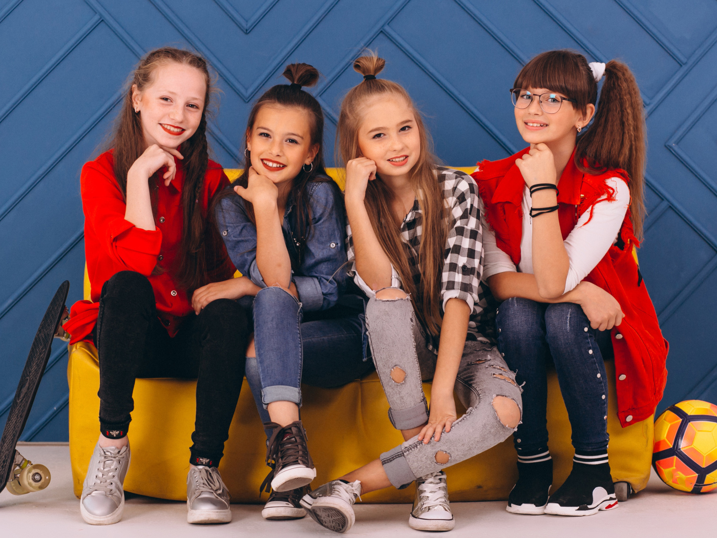 Четыре модных девочки сидят на диване 