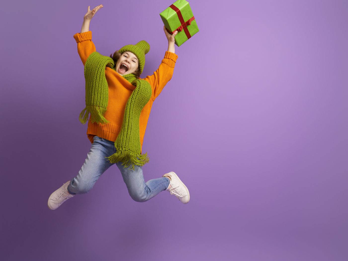 Счастливая девочка с подарком в руке на фиолетовом фоне