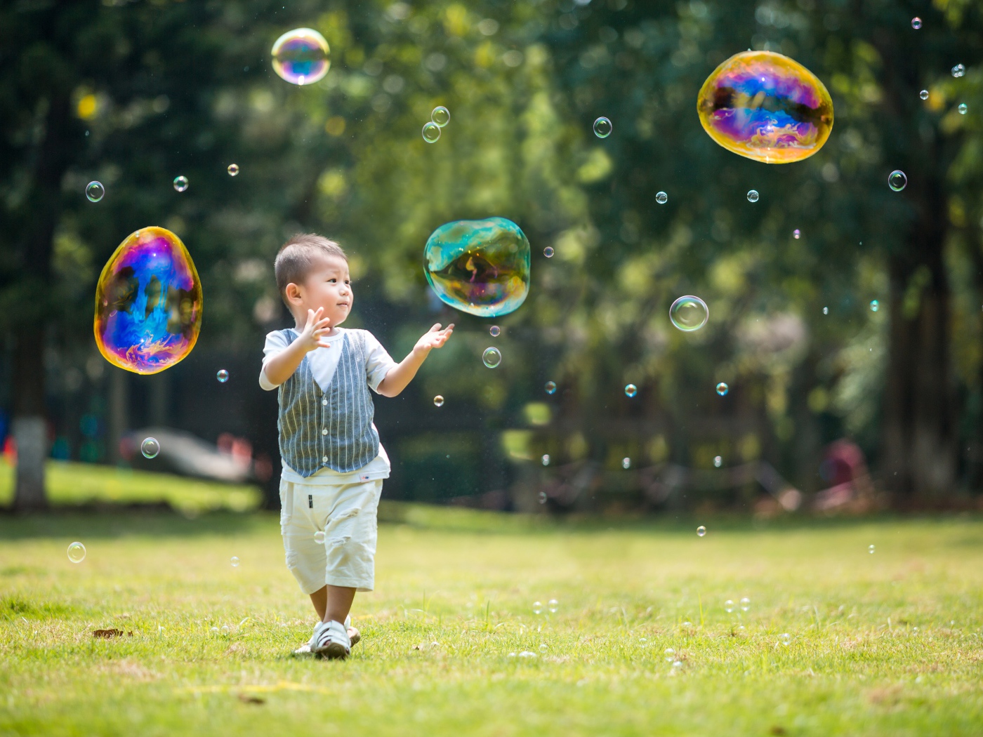 Маленький мальчик ловит мыльные пузыри