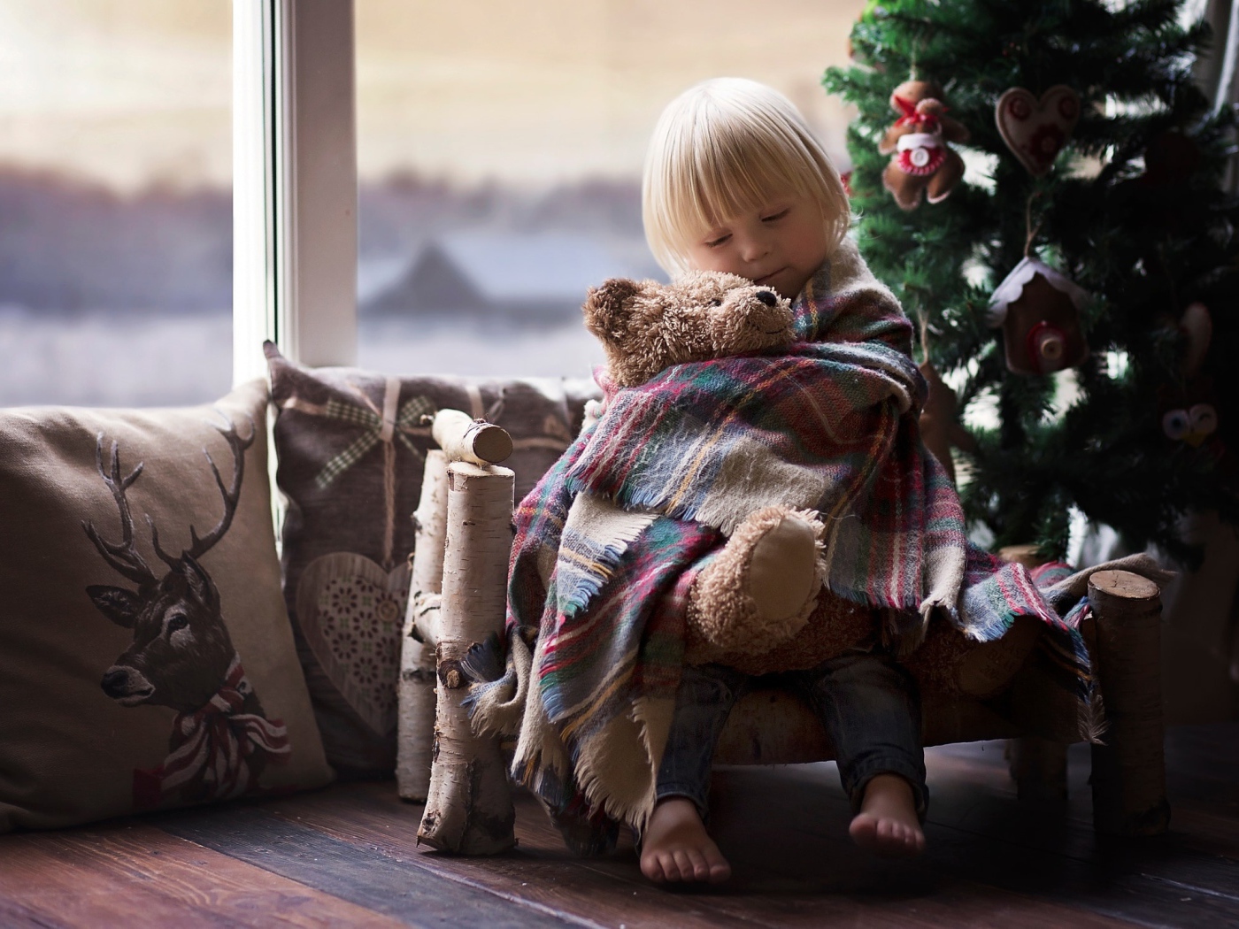 Маленькая девочка обнимает мишку у ели