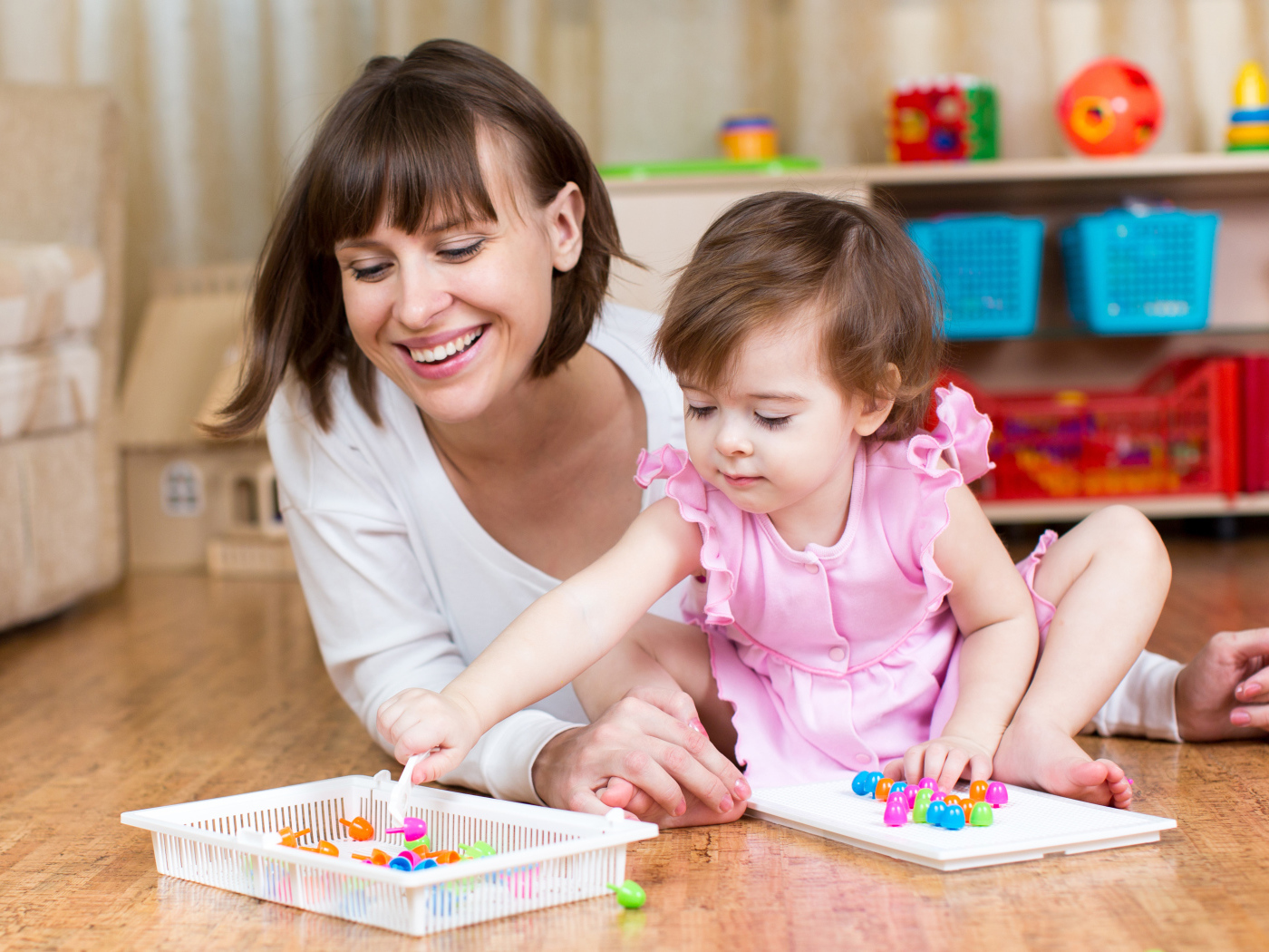 Маленькая девочка в розовом платье играет с мамой