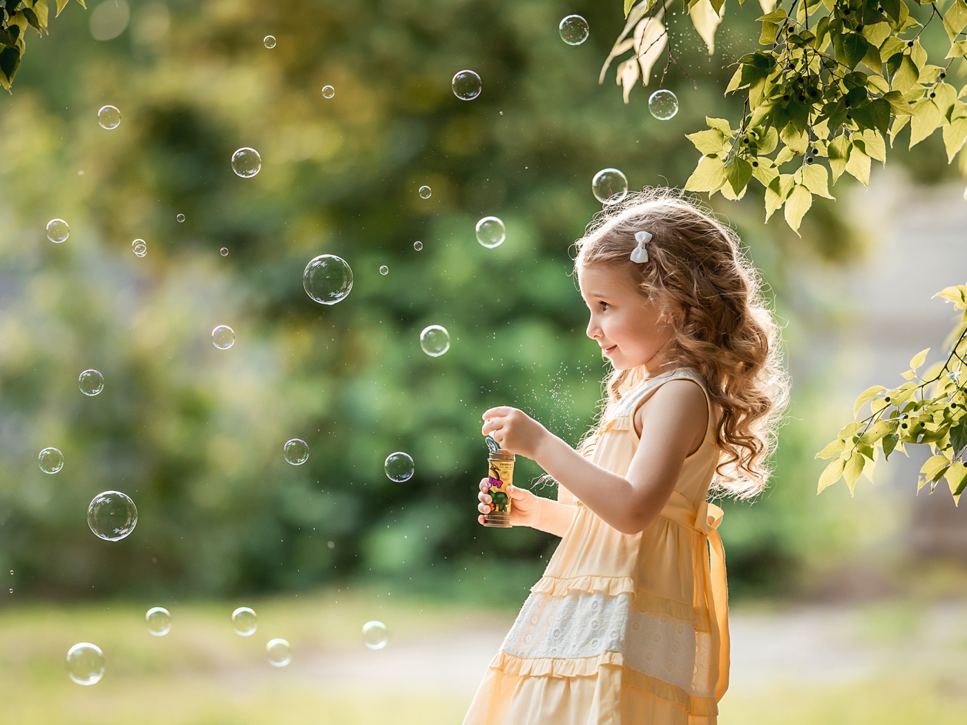 Маленькая девочка с мыльными пузырями в саду 