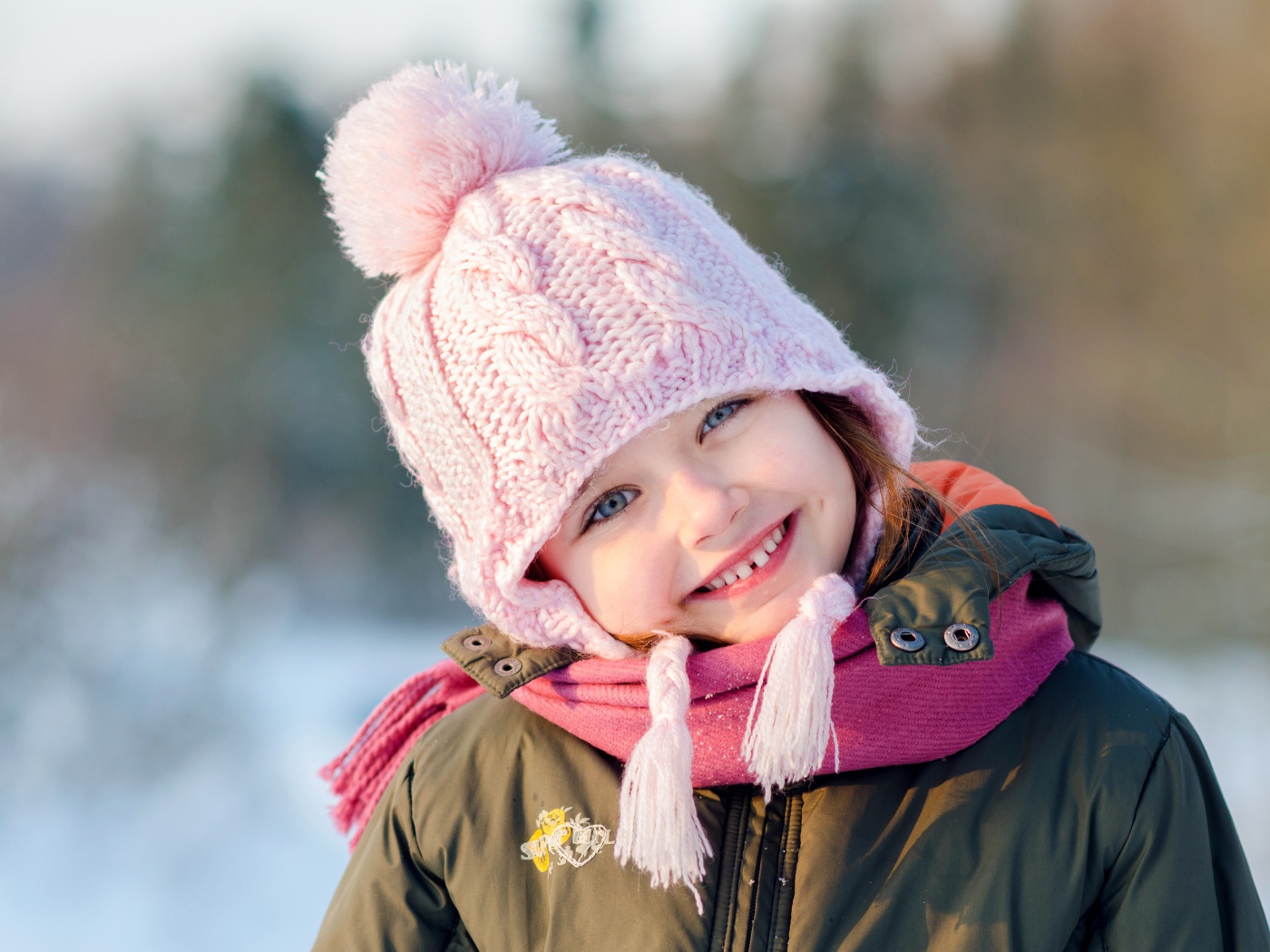 Улыбающаяся девочка в розовой шапке зимой