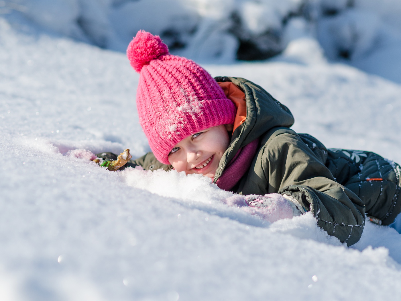 Улыбающаяся девочка лежит на снегу