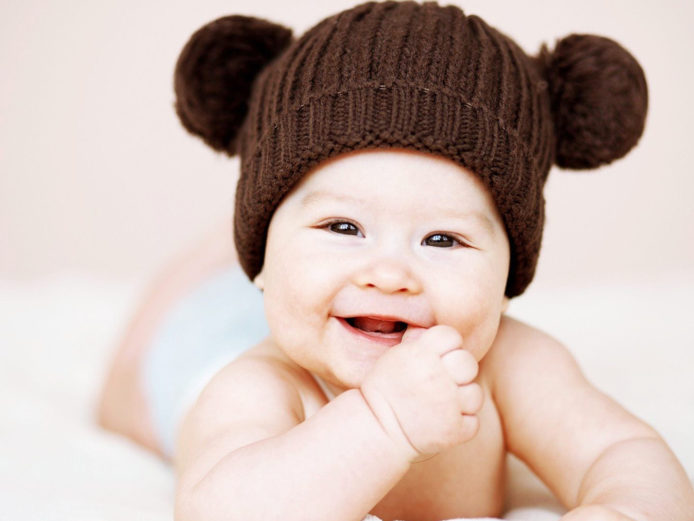 Улыбающийся грудной ребенок в коричневой шапке