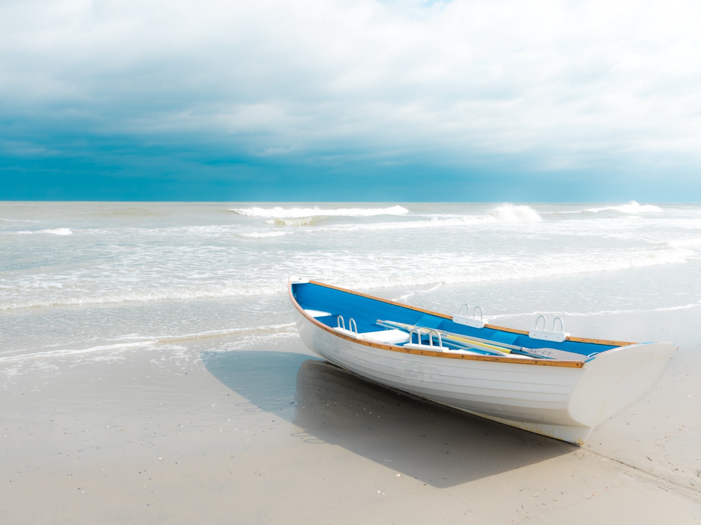 Лодка стоит на белом песке у моря 