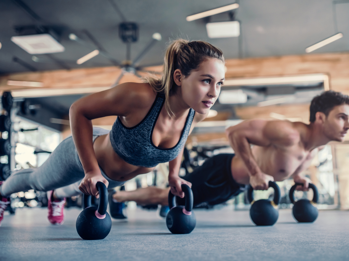 Парень и девушка занимаются с гирями в спортзале 