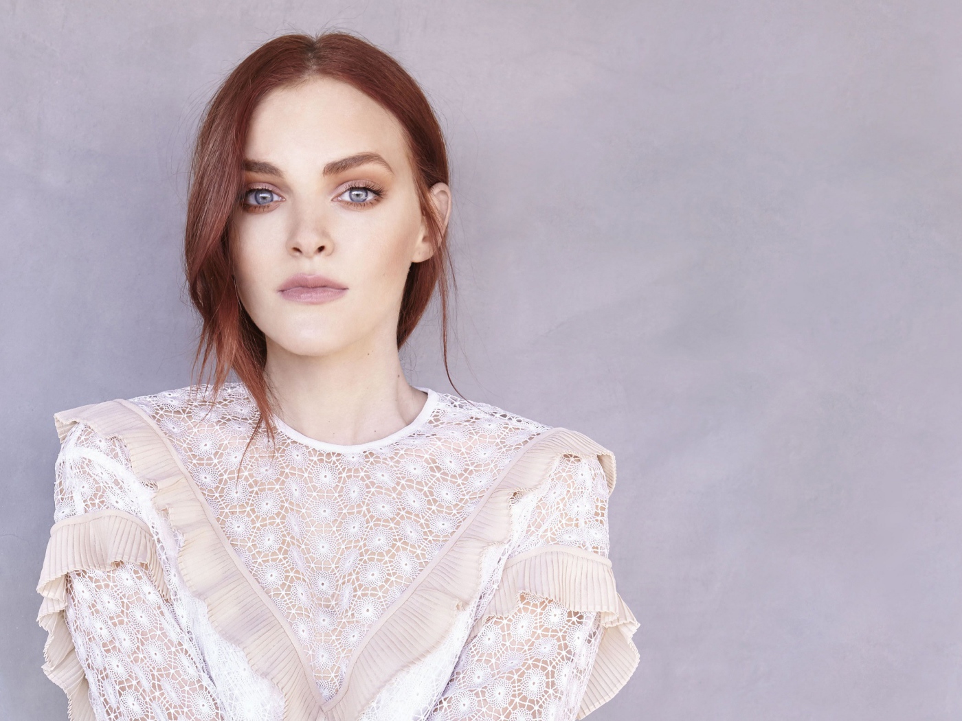 Актриса Мадлен Брюэр в белом платье на фоне стены