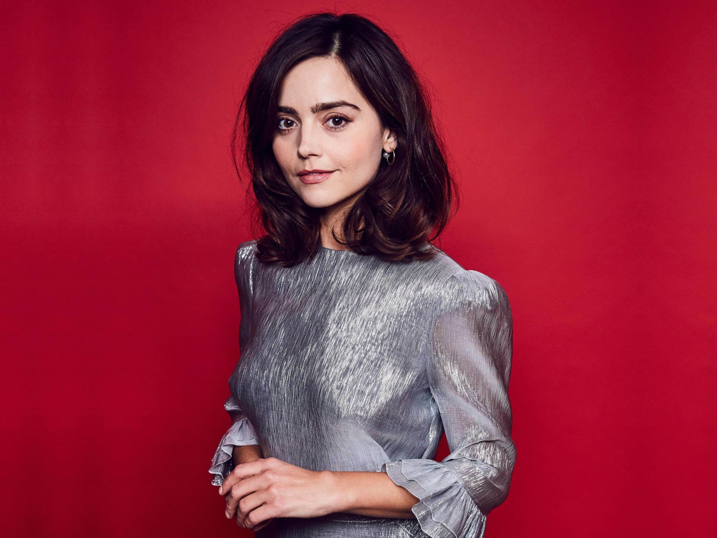 Американская актриса Дженна Коулман в сером платье на красном фоне