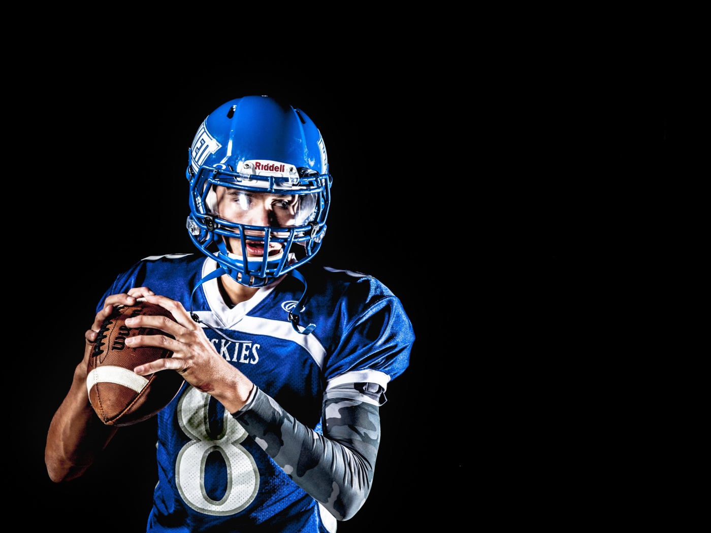 Игрок в американский футбол с мячом в руках на черном фоне 