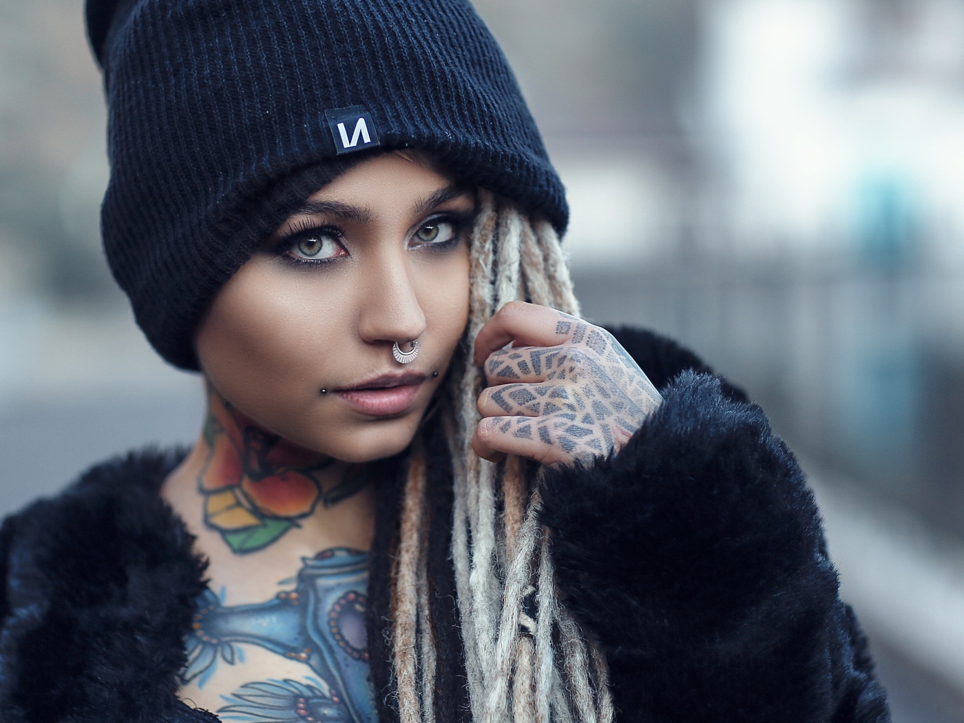 Красивая девушка в черной шапке с татуировками на теле 
