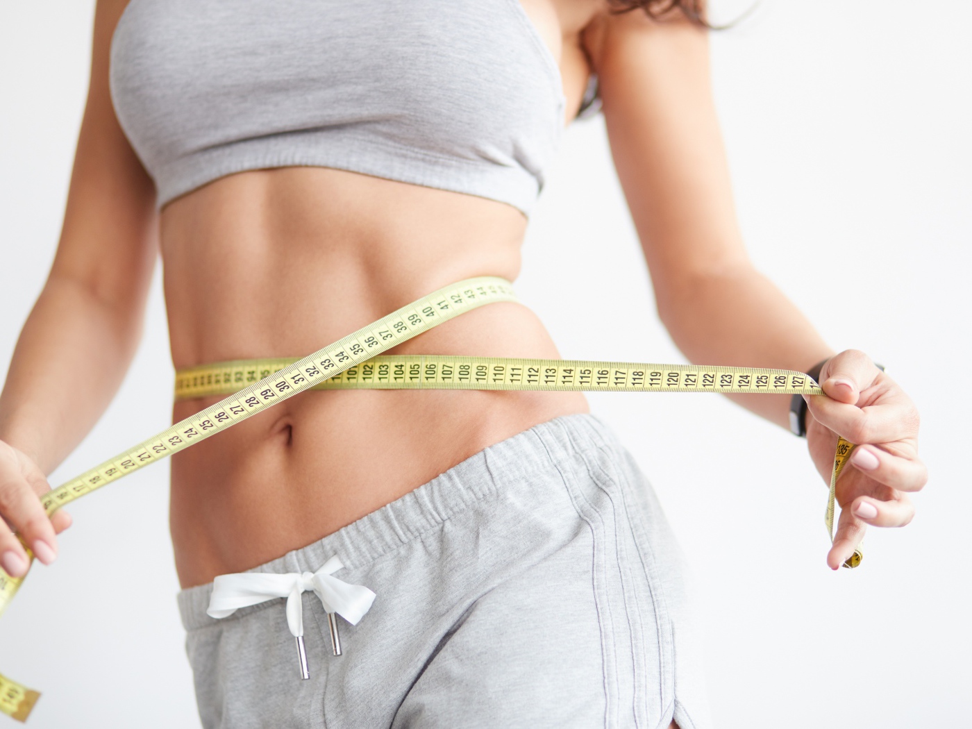 Красивая стройная девушка меряет талию сантиметром 
