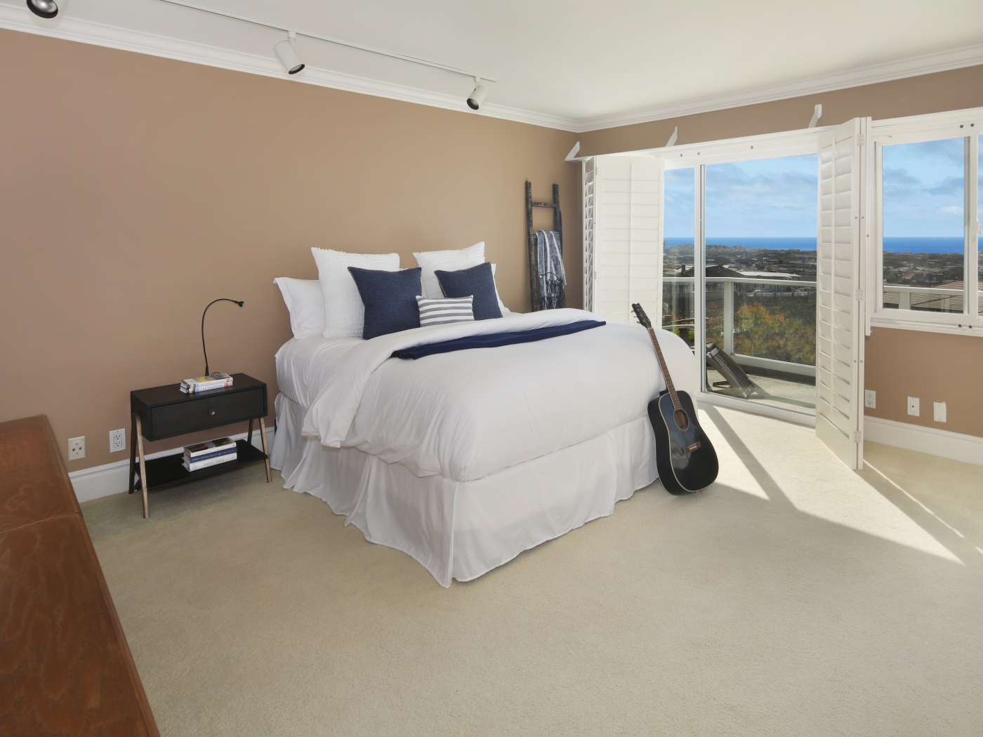 Большая высокая кровать в просторной спальне с гитарой 