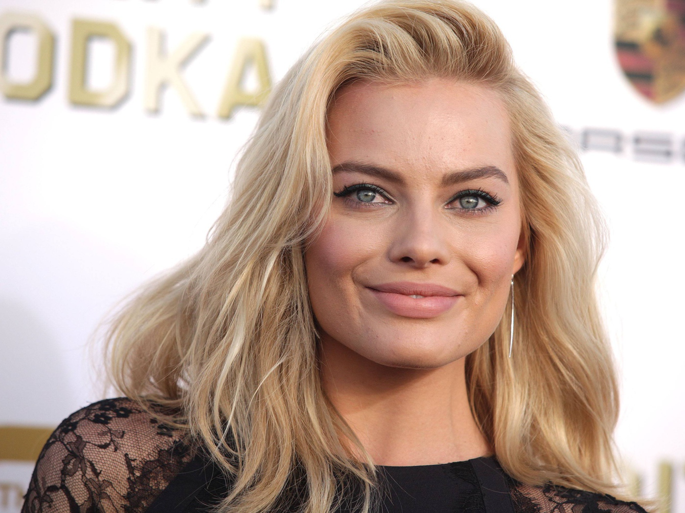 Улыбающаяся блондинка, актриса Марго Робби у стены