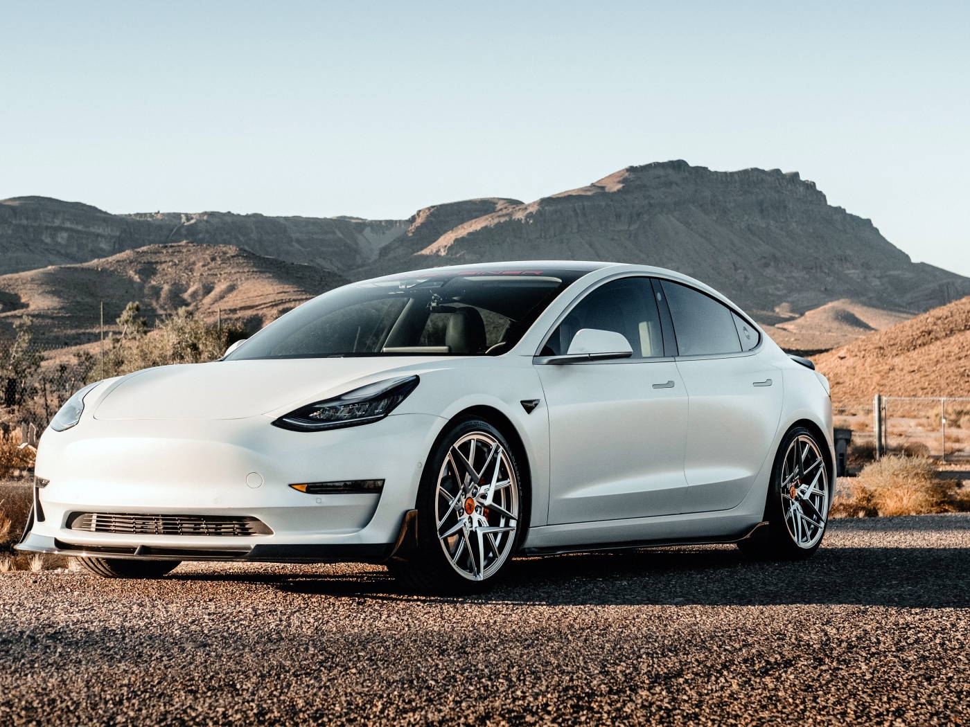 Белый автомобиль Tesla Model 3 Volta 2019 года на фоне гор 