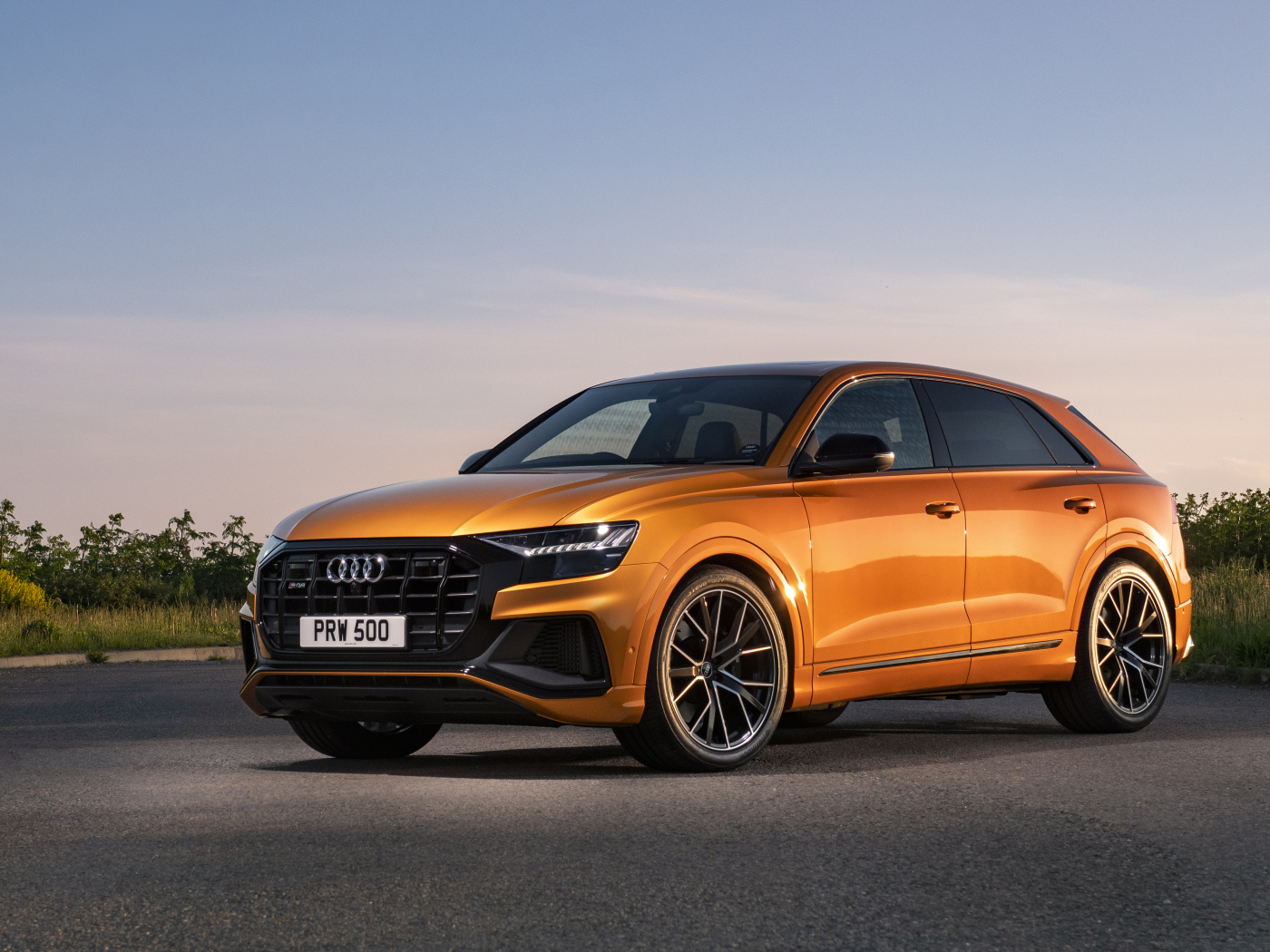 Оранжевый автомобиль Audi SQ8 TFSI 2021 года на фоне неба