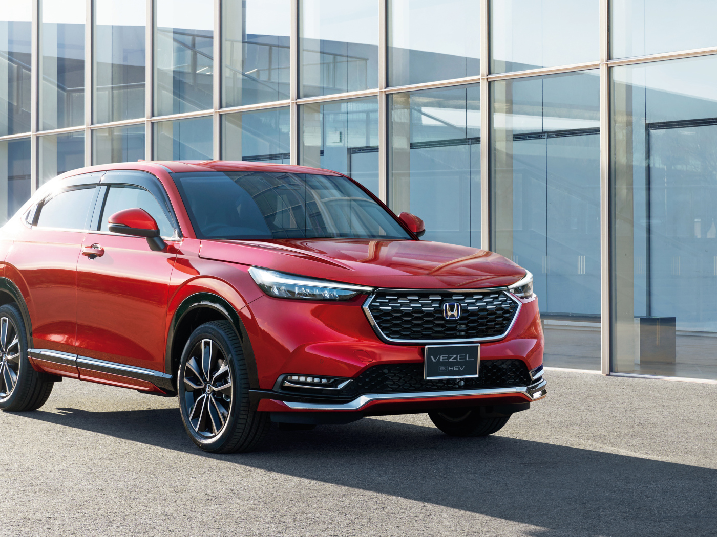 Красный автомобиль Honda Vezel EHEV 2021 у здания