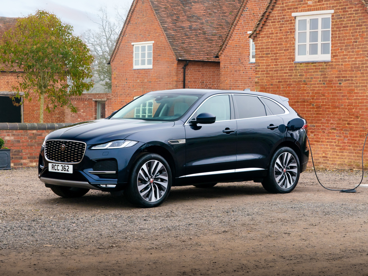 Черный дорогой автомобиль Jaguar F-Pace P400e AWD 2021 года, на заправке