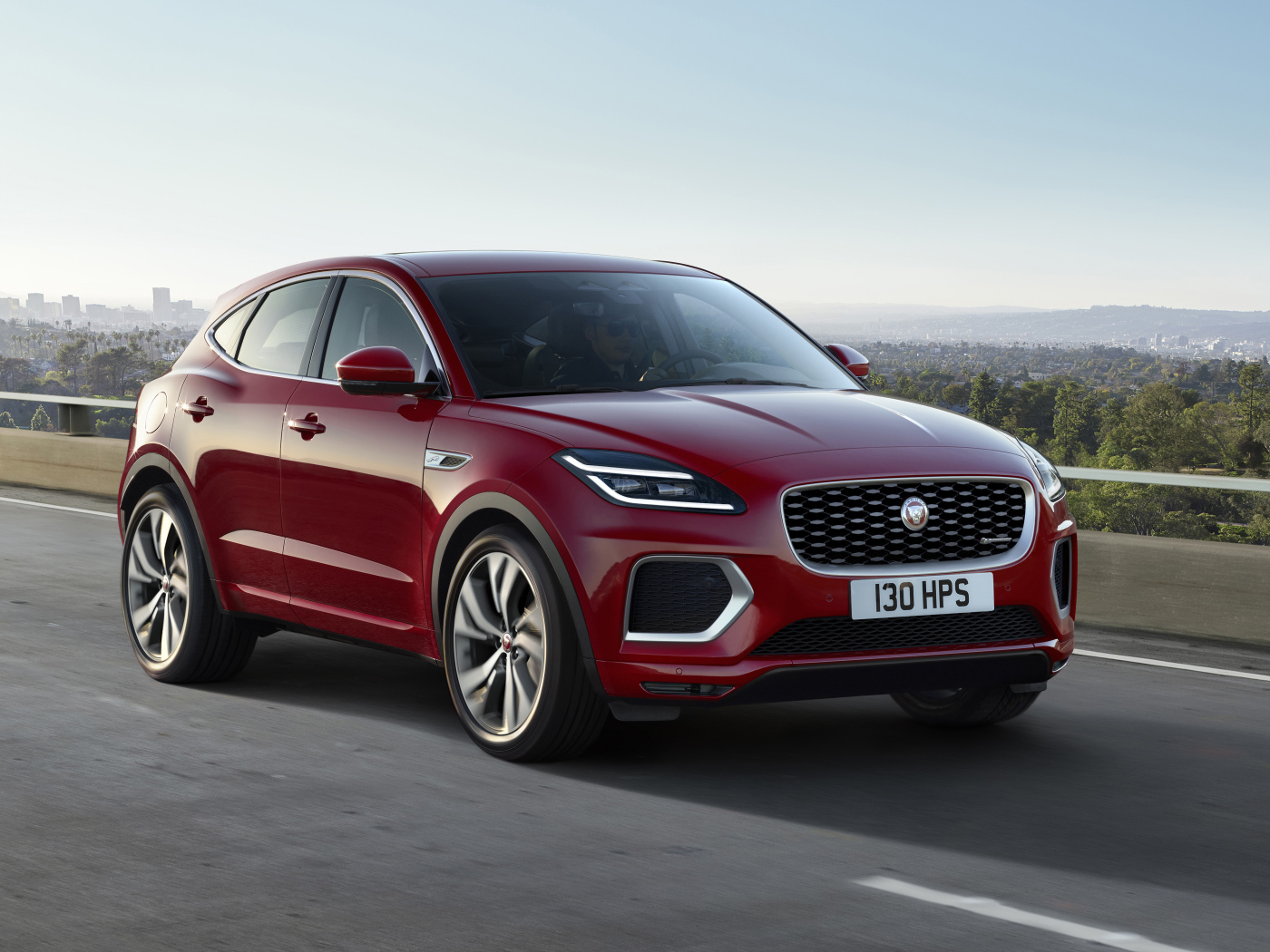 Красный автомобиль Jaguar E-Pace R-Dynamic 2021 года на мосту