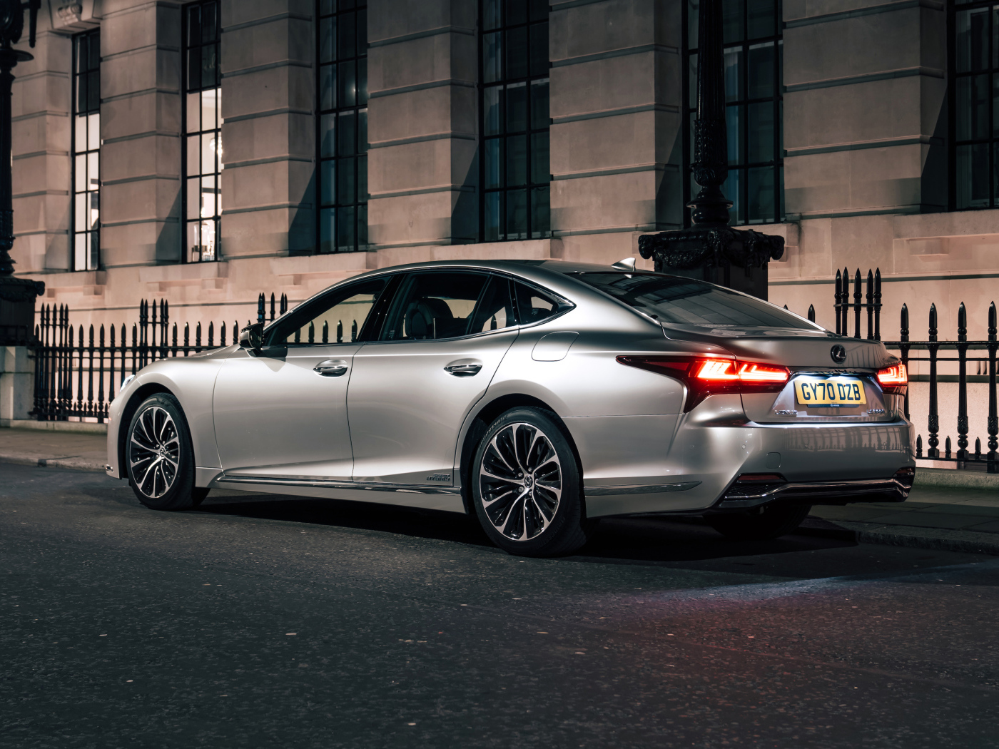 Серебристый автомобиль Lexus LS 500h 2021  года вид сзади