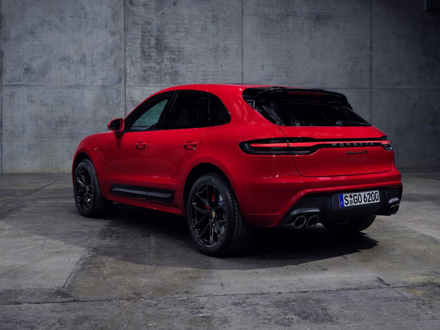 Красный автомобиль Porsche Macan GTS 2021 года на сером фоне вид сзади