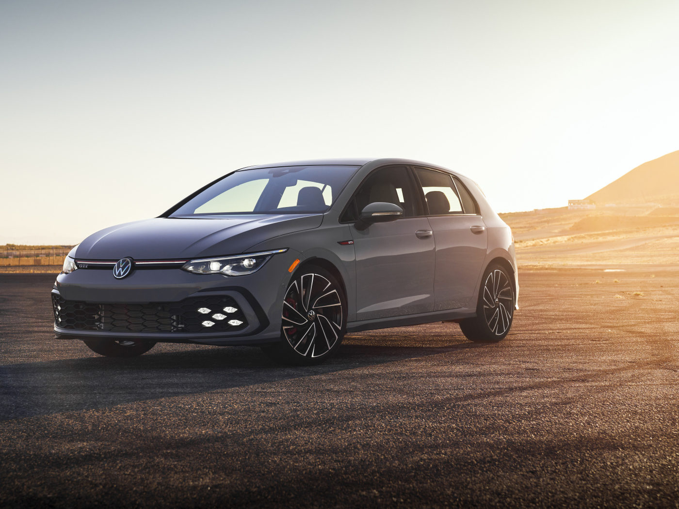 Серебристый автомобиль Volkswagen Golf GTI на фоне заката