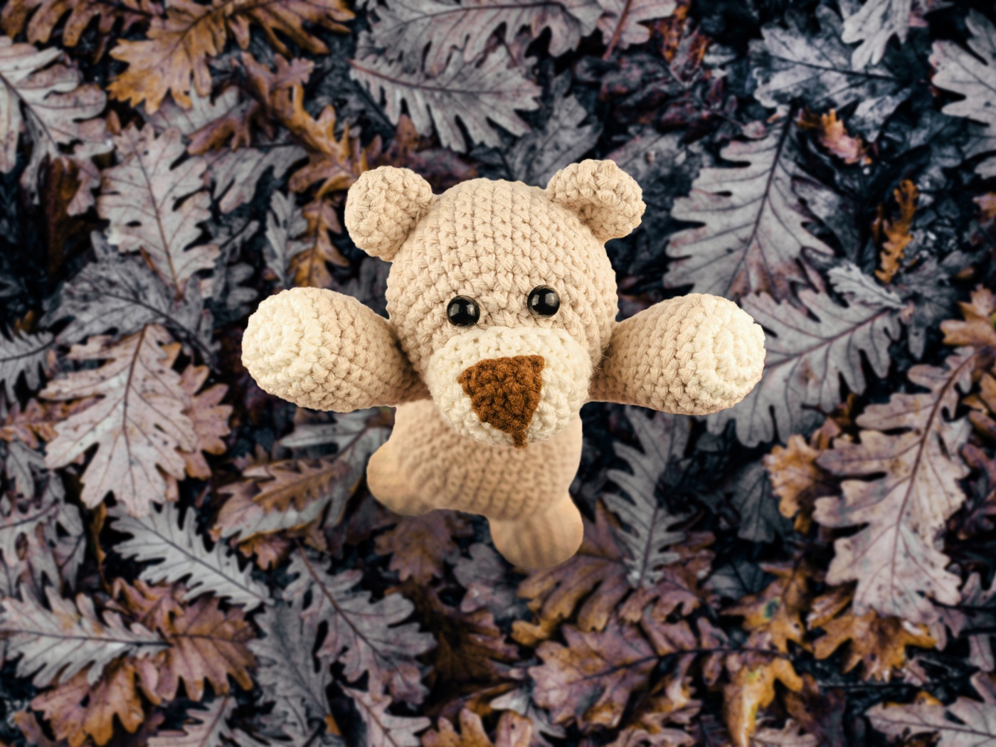 Knitted toy teddy bear on foliage