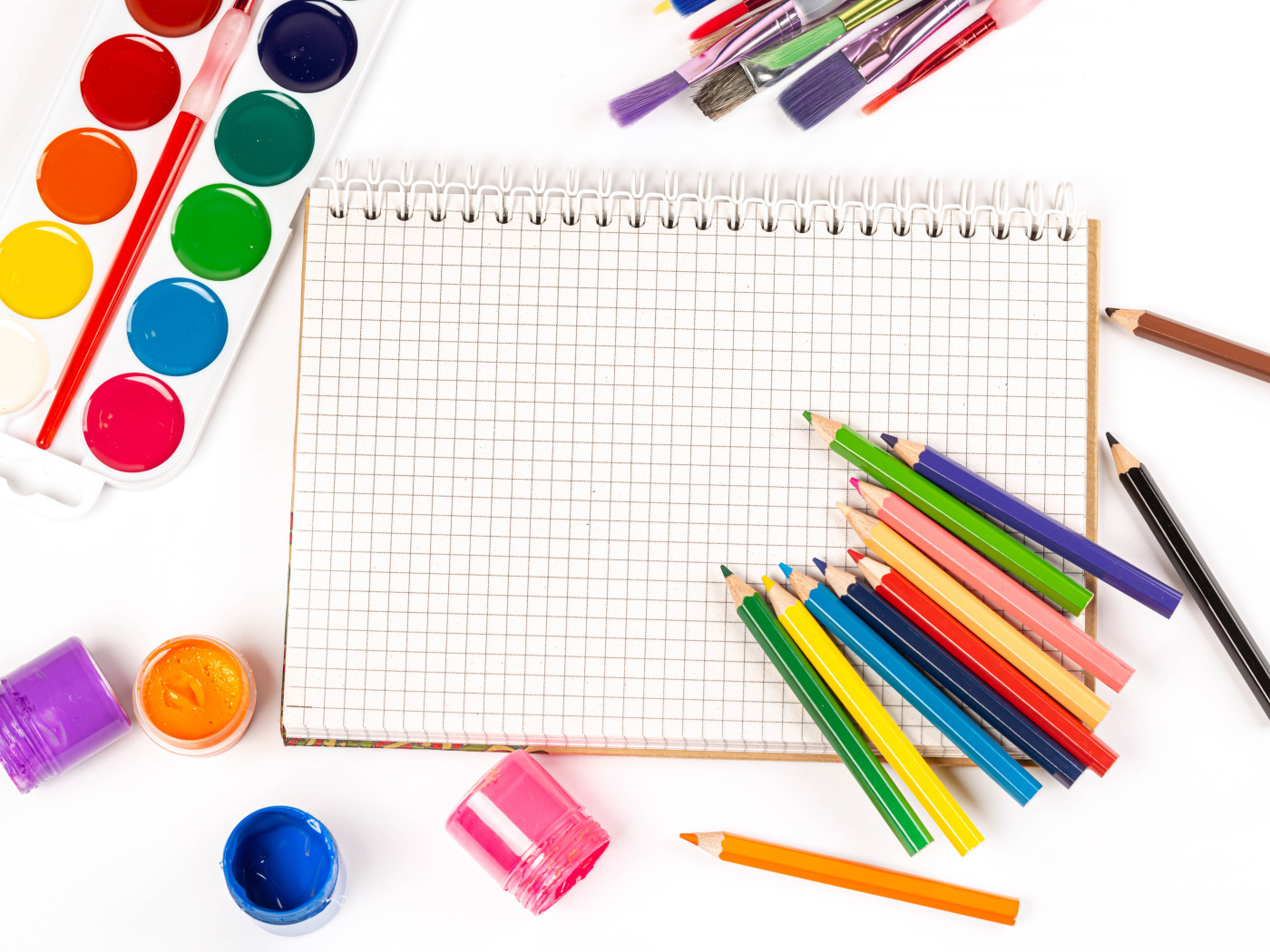 Карандаши, краски и тетрадь на белом фоне 