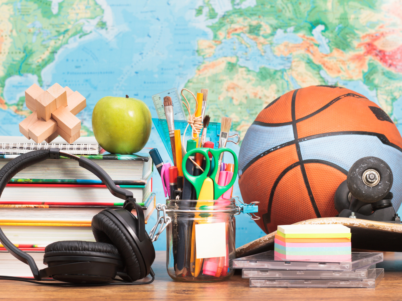 Школьные принадлежности на столе с наушниками и мячом 