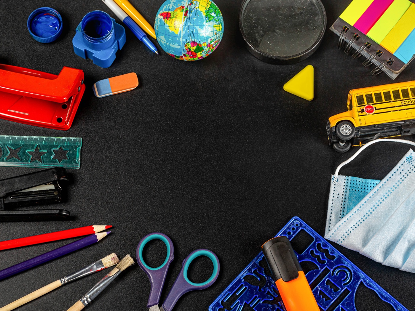 Канцелярские предметы, игрушки и маска на черном столе 