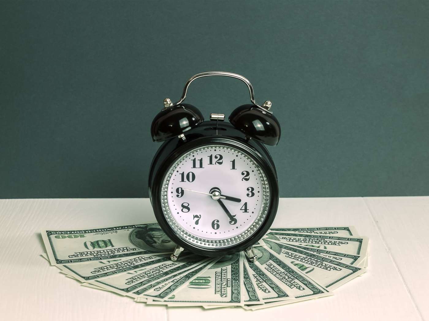 Черный будильник и доллары на столе