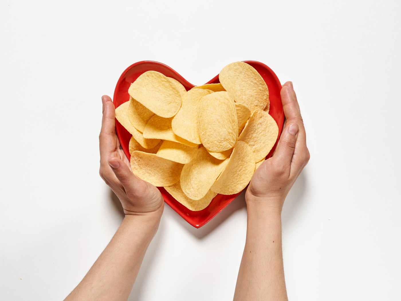 Чипсы в красной тарелке на белом фоне