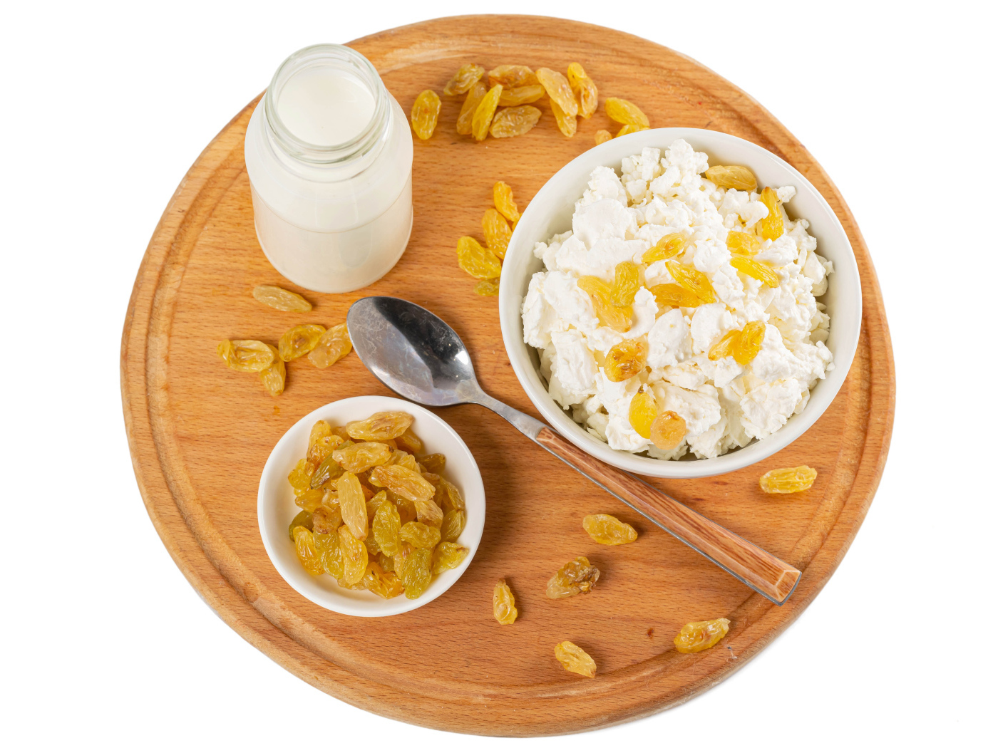 Творог с изюмом и молоком на доске на белом фоне 