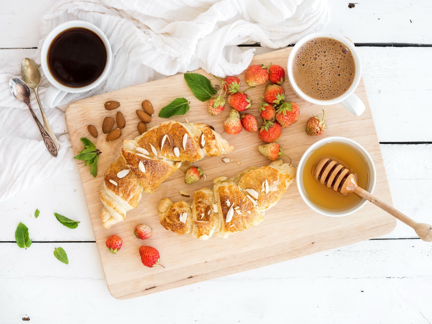 Круассаны на столе с орехами, клубникой и кофе