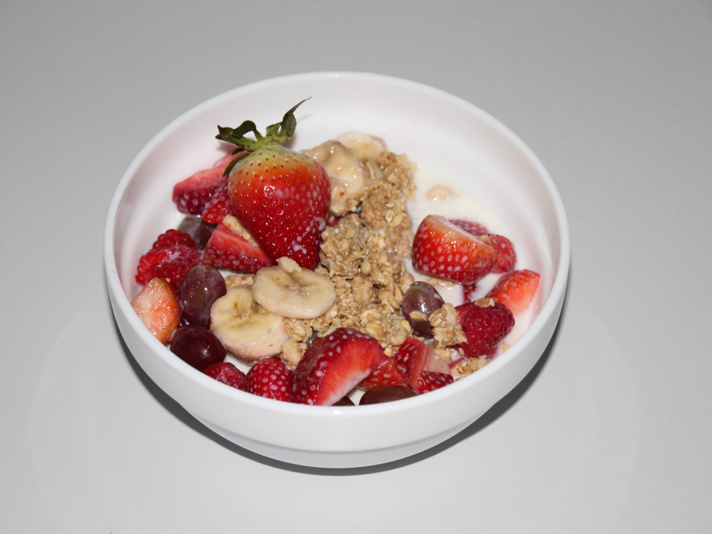 Мюсли с молоком и ягодами на сером столе