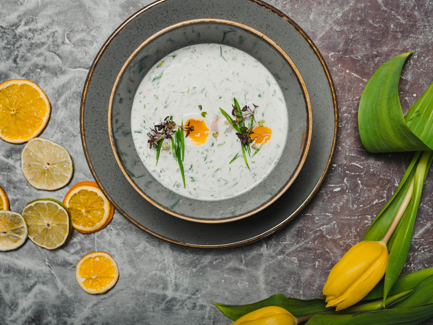 Окрошка на столе с лимонами и тюльпаном