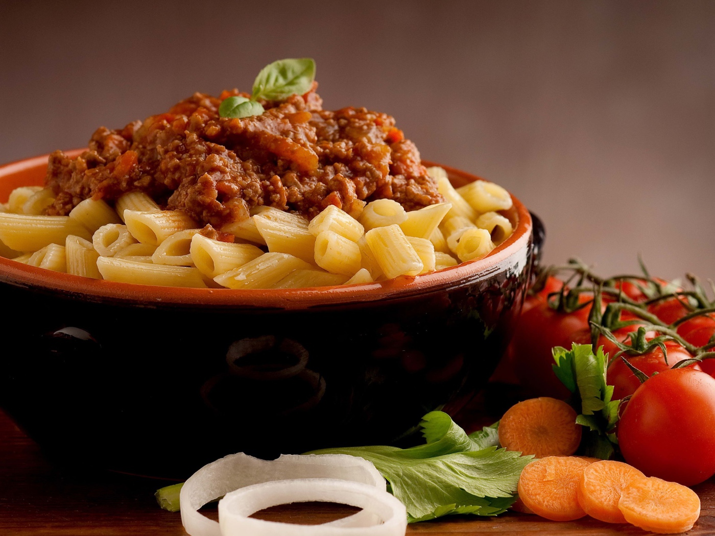 Макароны в миске с фаршем на столе с помидорами