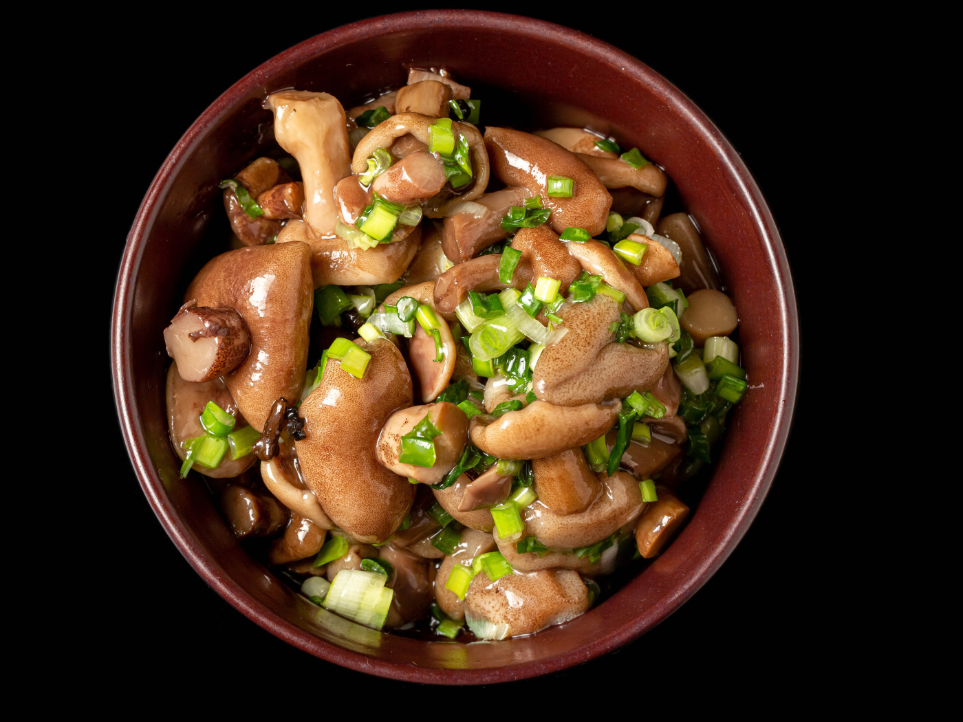 Маринованные маслята с зеленью в тарелке