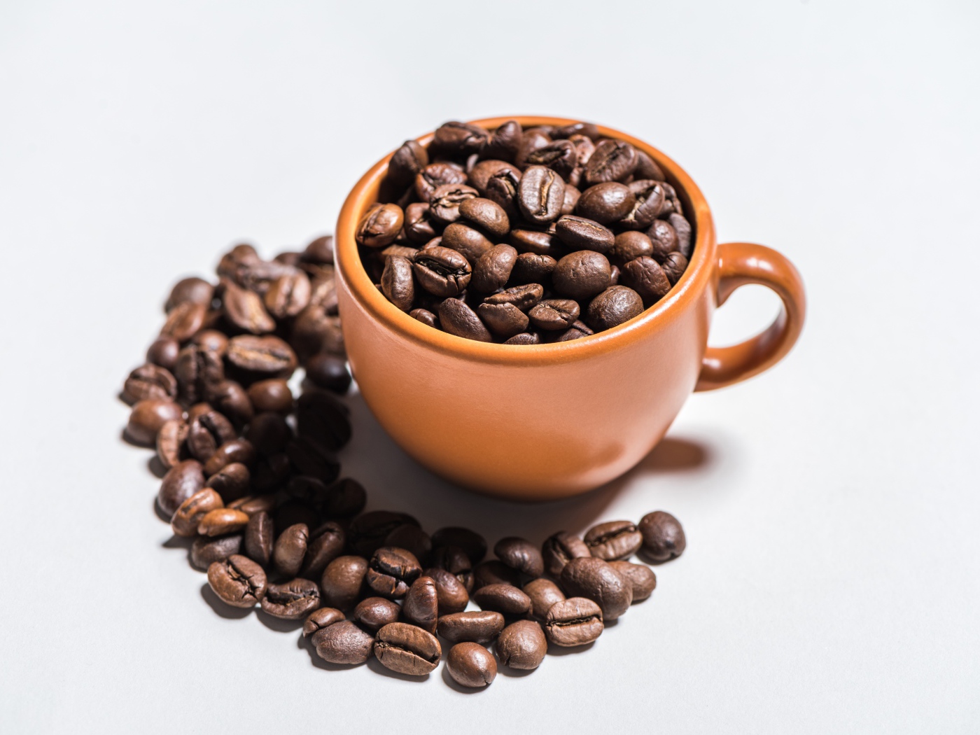 Жареные зерна кофе в кружке  на белом фоне