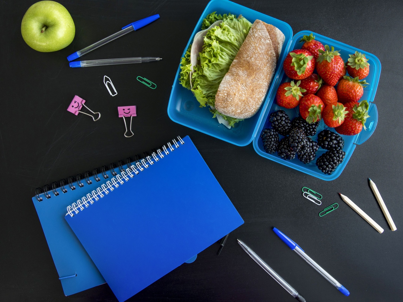 Сэндвич и ягоды в контейнере на столе с канцелярскими предметами